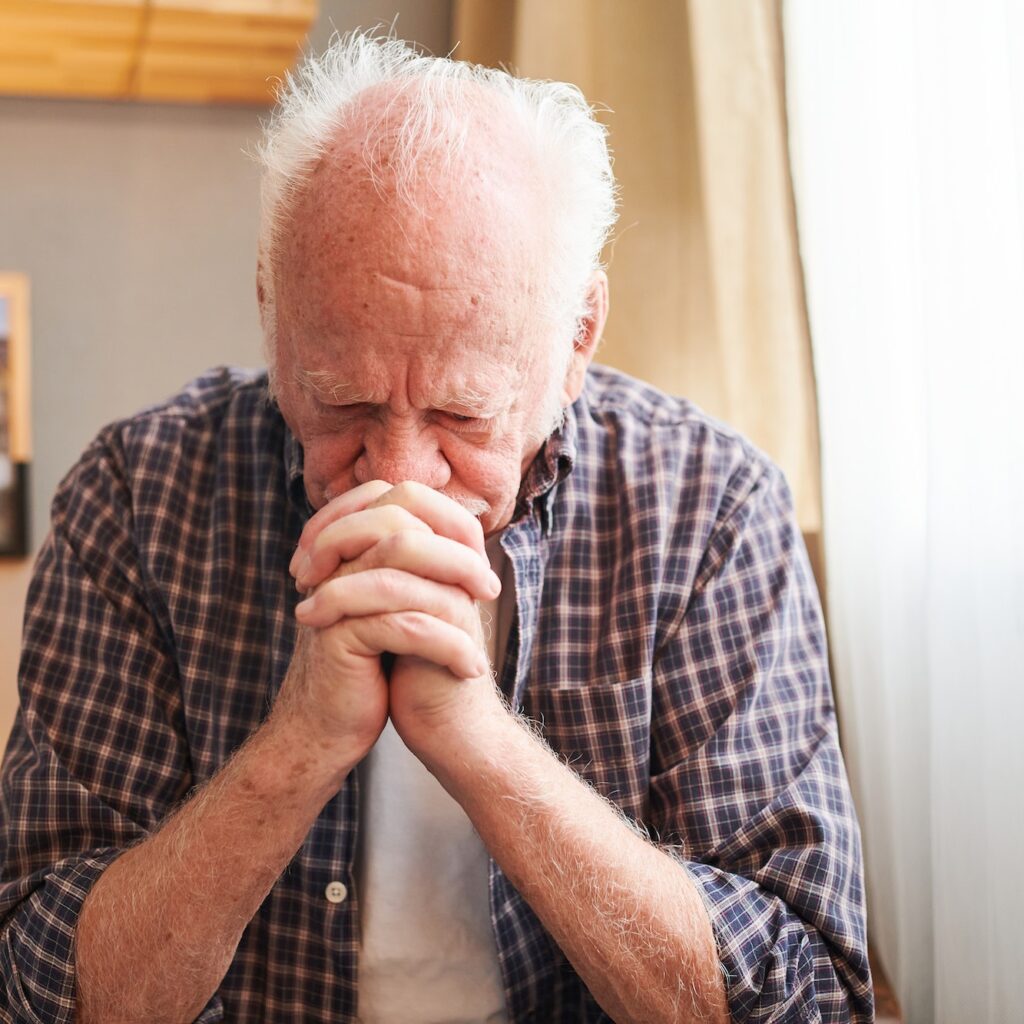 Sad old man sitting in his room